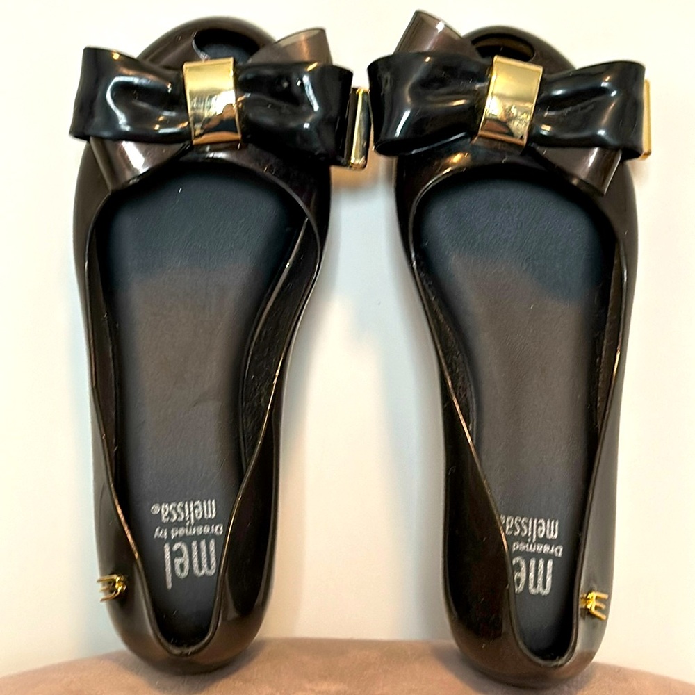 NWOT Melissa black flat with peep-toe window and black and gold bow in size 12.
